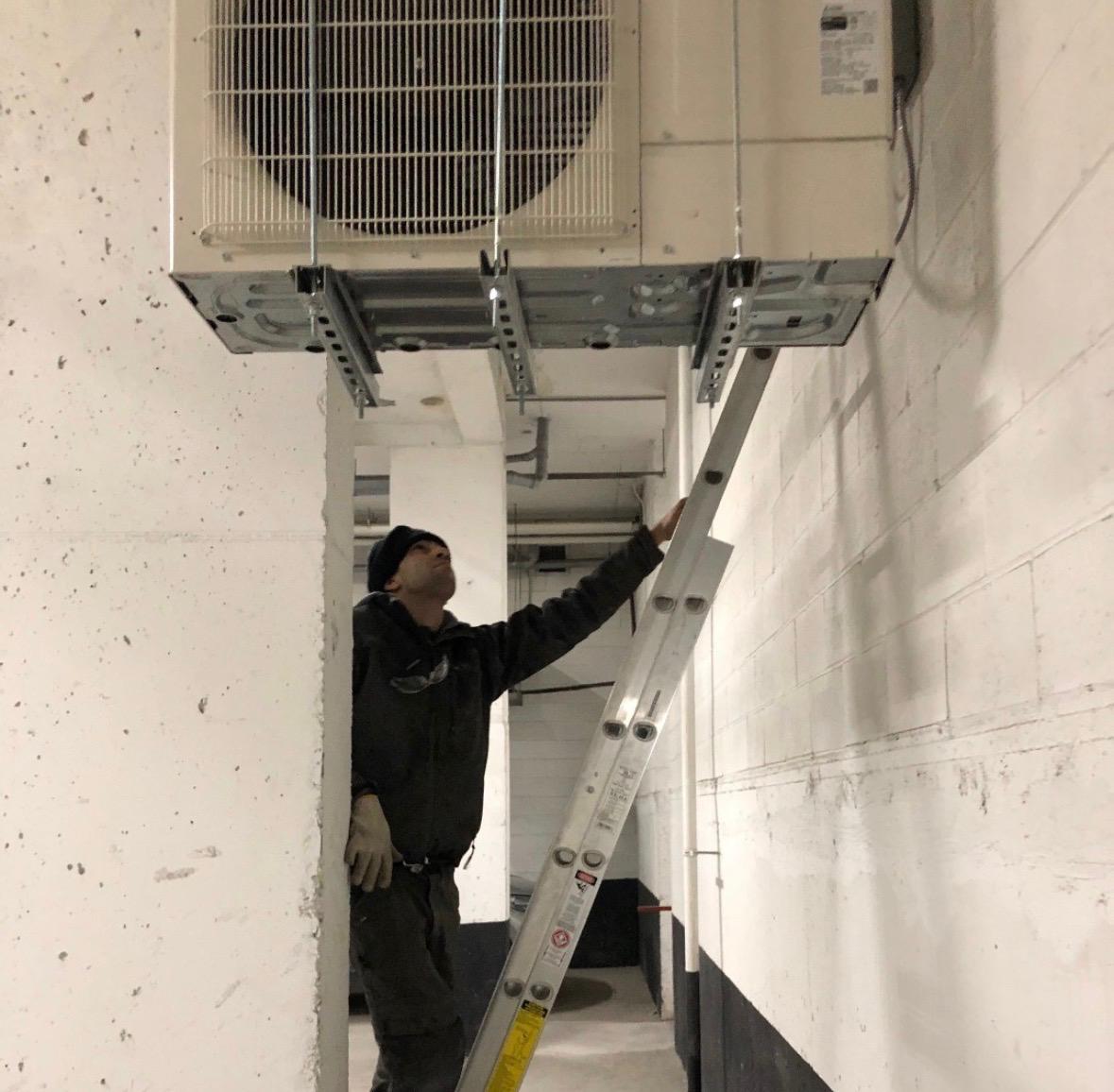 HVAC technician performing maintenance with a digital diagnostic gauge